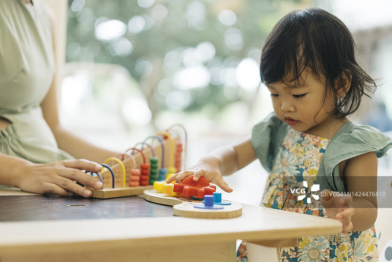 亚洲母亲教女儿玩蒙台梭利玩具特写图片素材