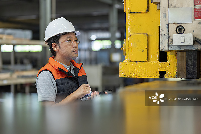 日本工程师在制造工厂使用平板电脑检查重型机器的功能图片素材