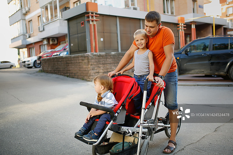 年轻的父亲和两个儿子在城镇骑自行车图片素材