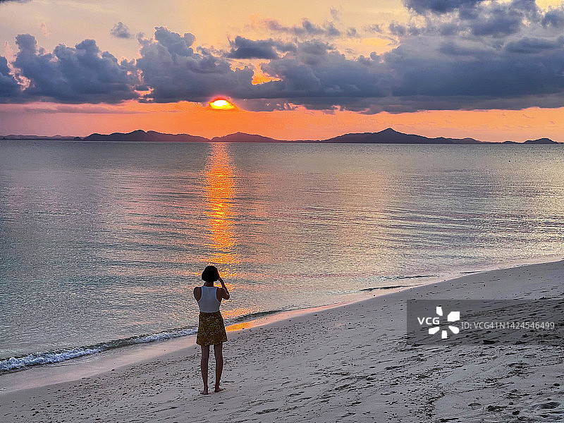 在热带岛屿上拍摄海滩日落的人图片素材