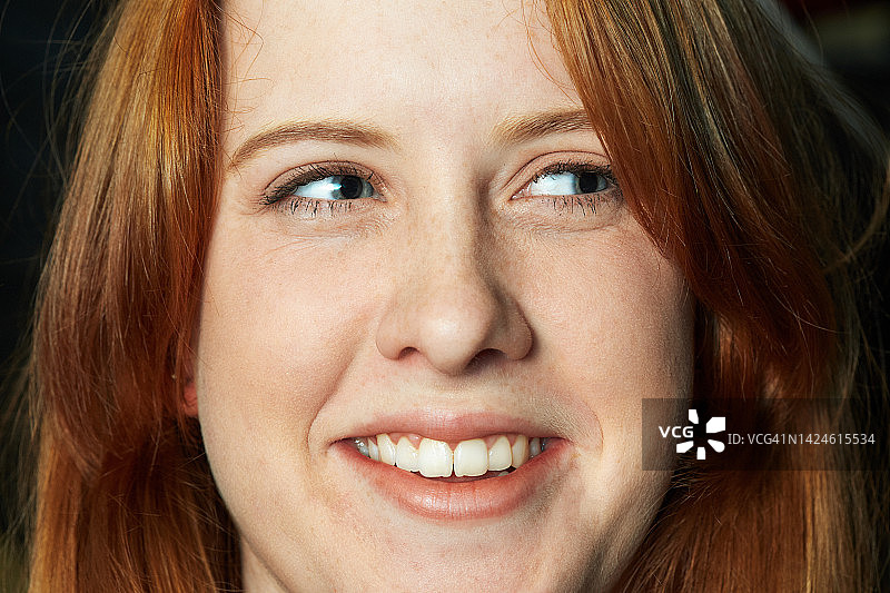 快乐的年轻红发女子笑着看向一侧图片素材