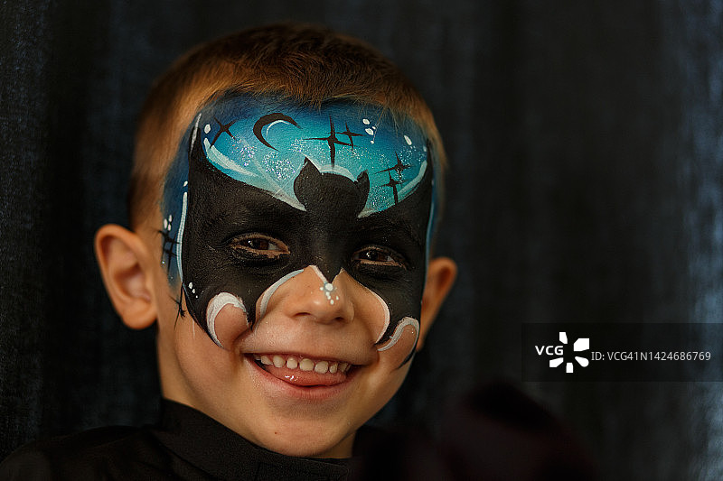 男孩化着脸部彩绘，准备参加万圣节派对图片素材