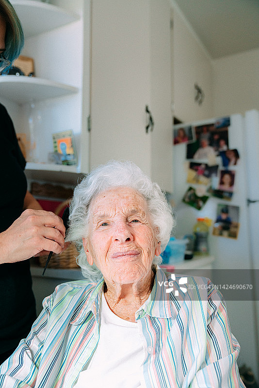 在家中由专业护理造型师梳头的可爱的年长白人妇女的广角镜头图片素材