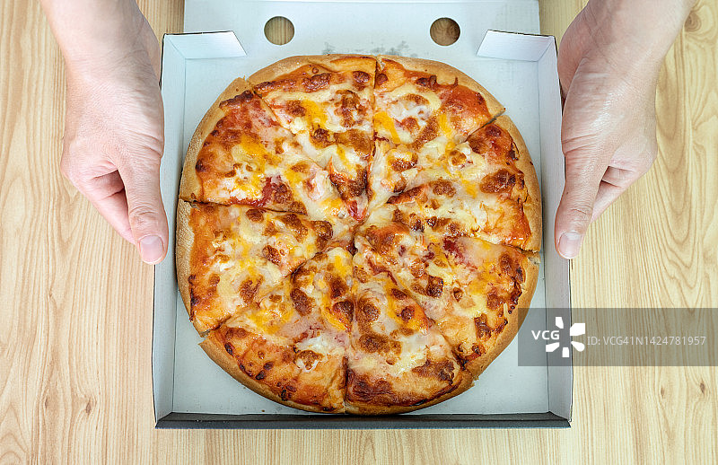 手持海鲜鸡尾酒披萨盒的俯视角度图片素材