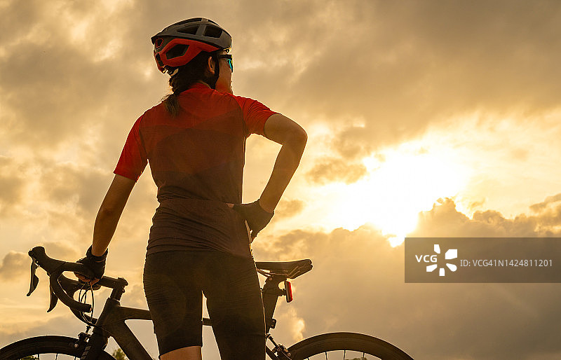 骑自行车锻炼时欣赏美丽日落的骑自行车女子图片素材