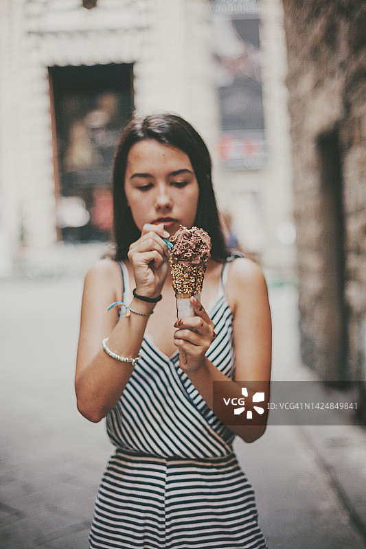 在街上吃融化巧克力甜筒冰淇淋的拉丁裔女子图片素材
