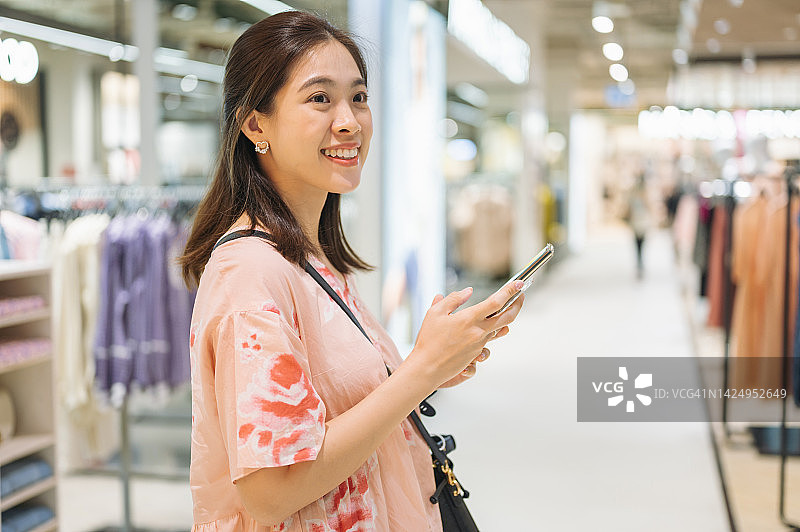 在商店使用购物APP查看价格和尺寸的亚洲中年男人图片素材