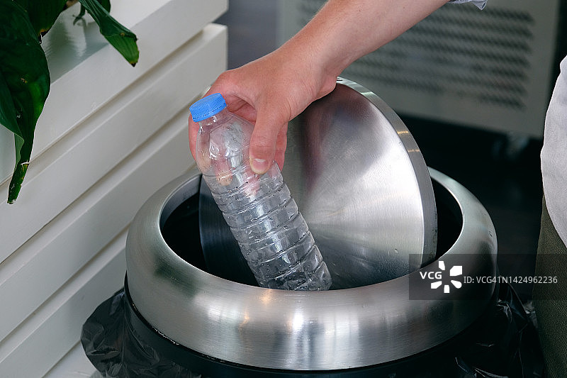 男子将旧空瓶扔进垃圾桶图片素材