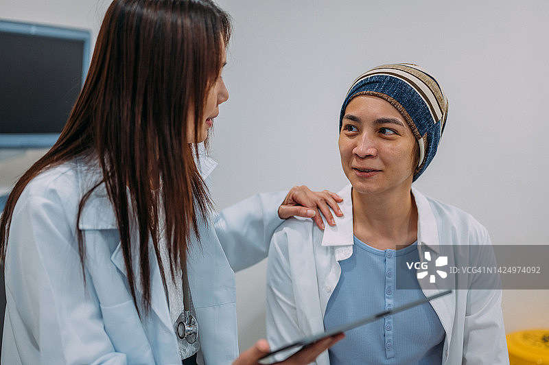 亚洲女妇科医生用平板电脑向患者讲解宫颈癌防治知识和检查结果图片素材