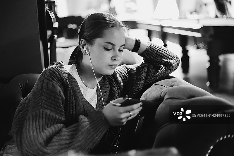 戴耳机玩手机看视频的女孩图片素材