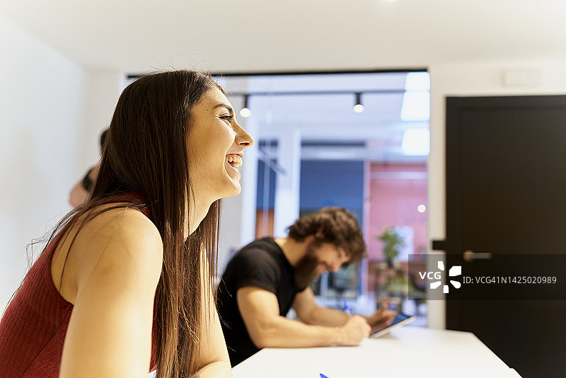 微笑的女大学生举手回答教授提出的问题图片素材