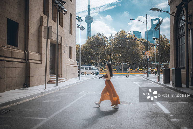 一位美丽的年轻亚洲女子在上海街头 carrying 相机拍摄照片图片素材