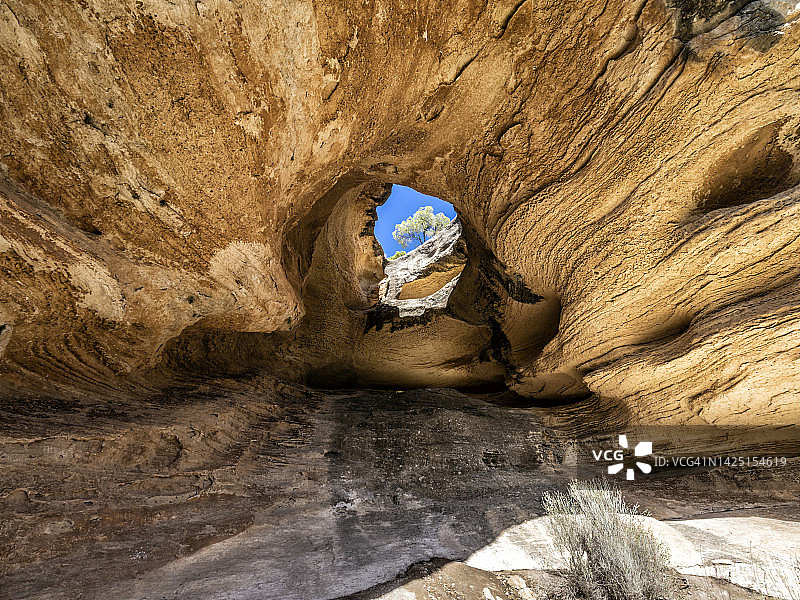 大型洞穴内部：阳光从天花板上的孔洞射入图片素材