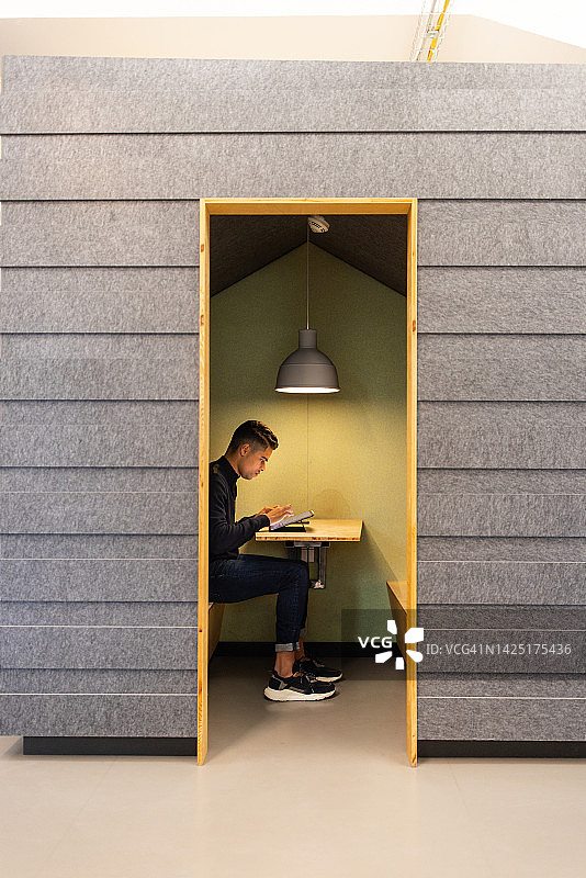 在小隔间里使用平板电脑工作的商人图片素材