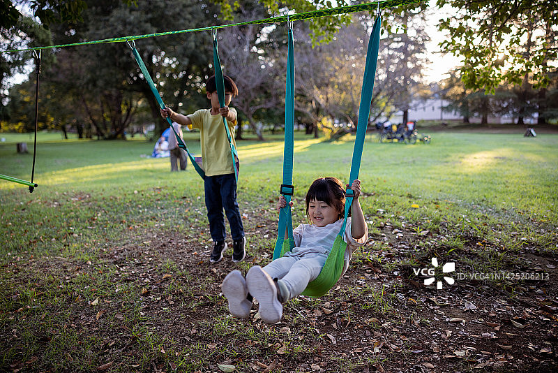 在公园荡秋千的弟弟和妹妹图片素材