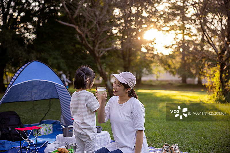 小女儿在公园里和妈妈碰杯图片素材