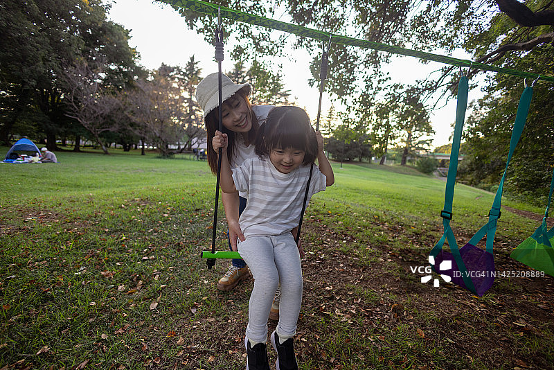 母亲在公园的秋千上和女儿玩耍图片素材