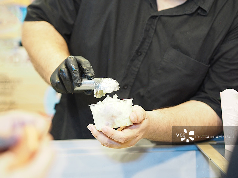 用勺子将冰淇淋舀入杯中图片素材