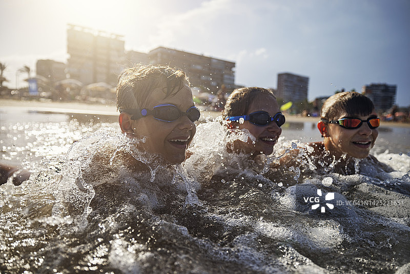 三个青少年在西班牙阿利坎特的海边玩水嬉戏图片素材