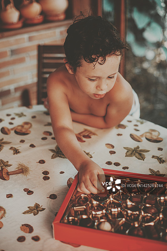 男孩赤膊伸手拿桌子上的巧克力松露图片素材