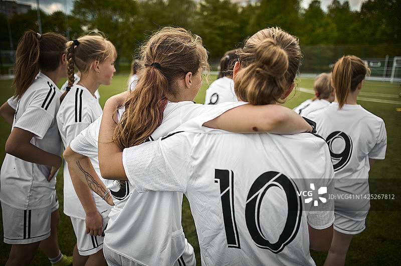 少女足球队成员在运动场拥抱图片素材