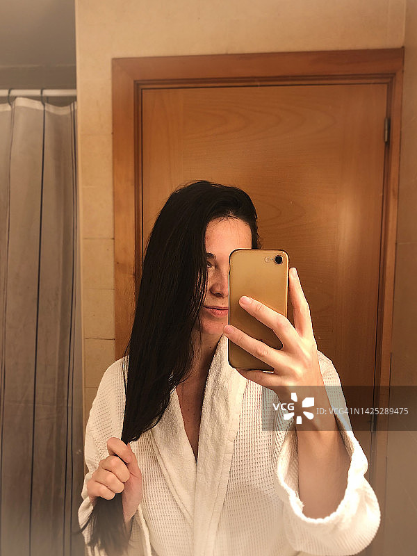在浴室里穿着浴袍自拍的女人图片素材