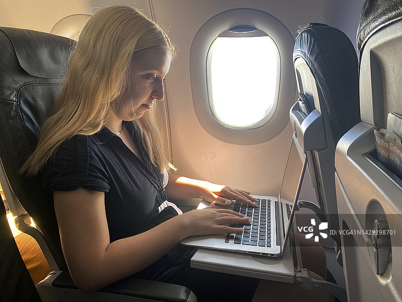 女乘客在飞行中使用笔记本电脑图片素材