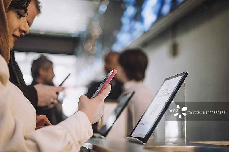 女商人用智能手机扫描二维码，同事在前台图片素材