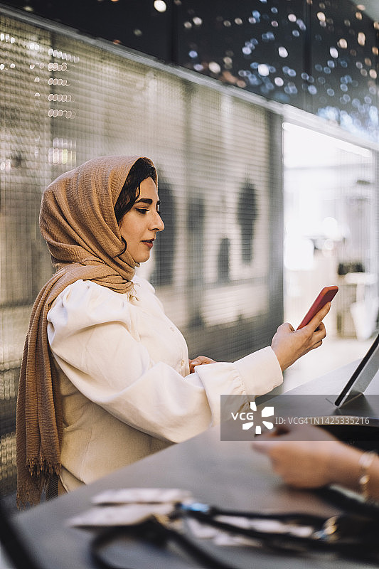 中年女商人在前台用手机扫描二维码图片素材