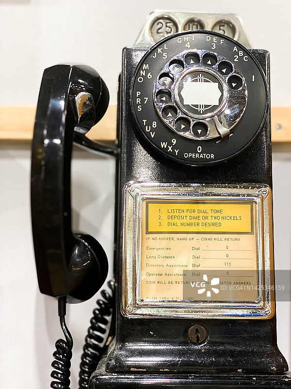 墙上的老式黑色旋转拨号公用付费电话图片素材