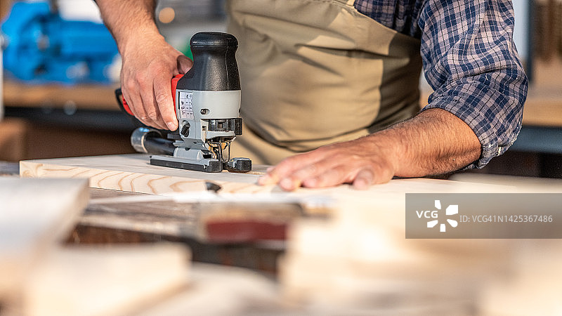 男人用曲线锯切割木材图片素材