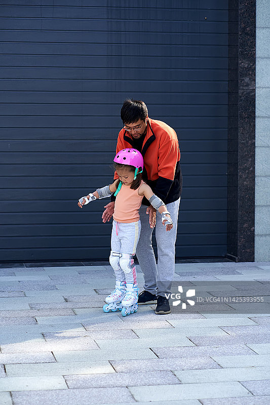 父亲教女儿在家附近玩滑旱冰图片素材