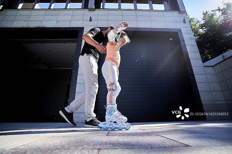 阳光下，父亲教女儿滑旱冰图片素材