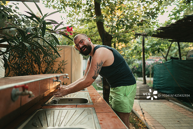 男人在度假露营地水槽洗手图片素材