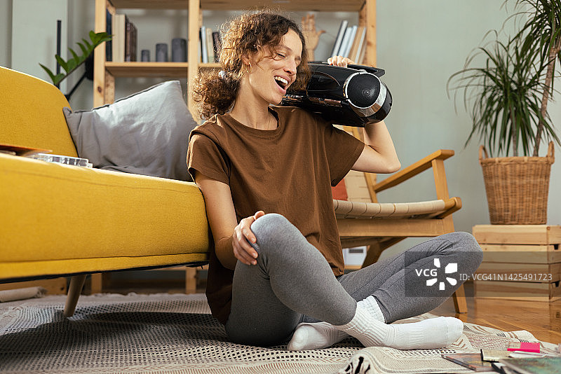 快乐的年轻女人用老式便携式立体声音响欣赏音乐图片素材