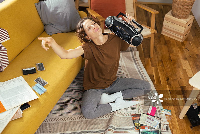 快乐的年轻女人在家中享受乐趣，用旧便携式音响听音乐图片素材