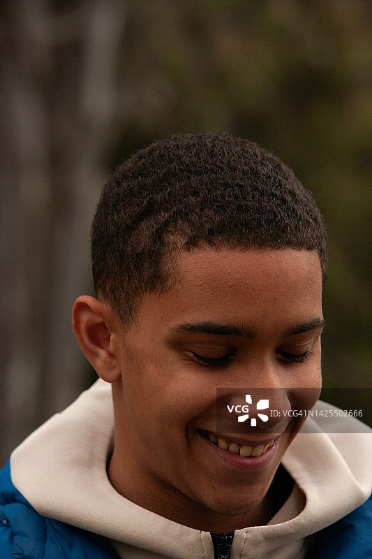 一位身穿蓝色羽绒服和奶油色连帽衫的快乐英俊少年图片素材