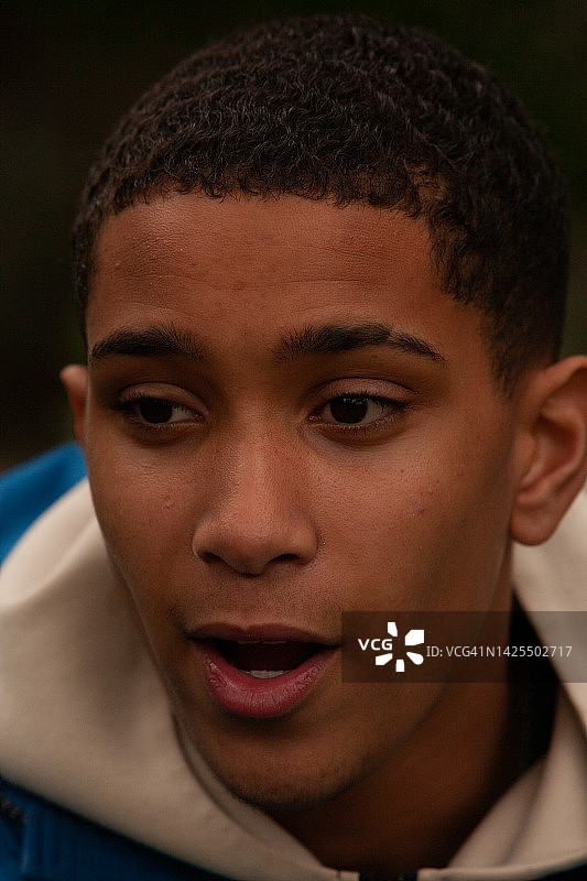 快乐的年轻男子，穿着蓝色夹克和奶油色连帽衫的青少年图片素材