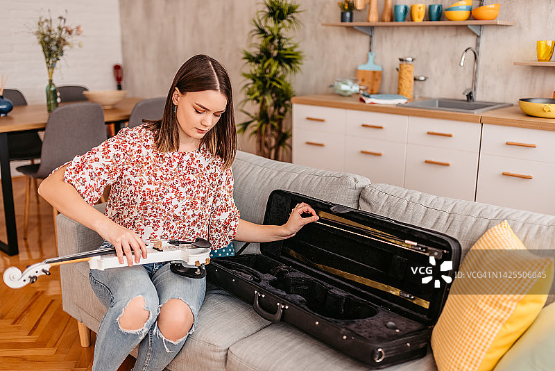 从琴盒里拿出小提琴的年轻女人图片素材
