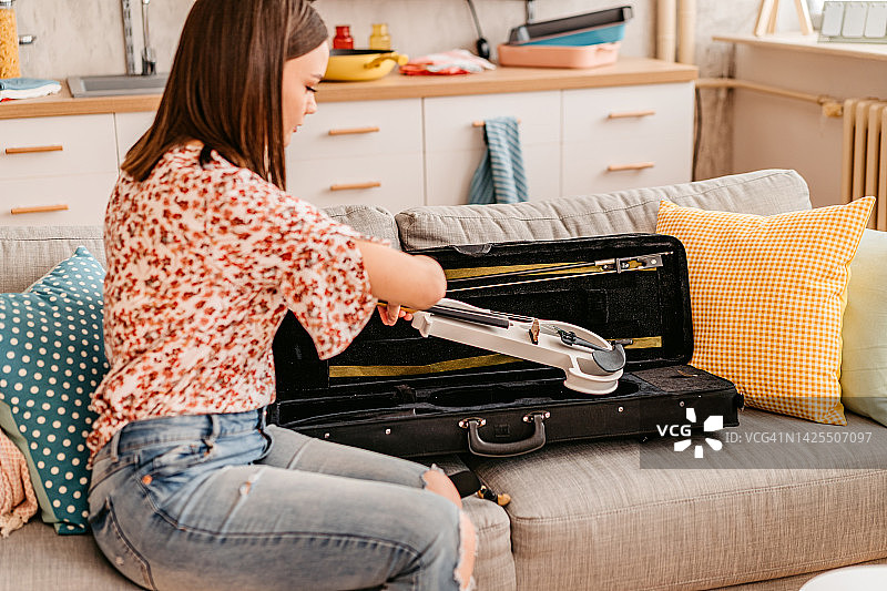 从琴盒里拿出小提琴的年轻女人图片素材