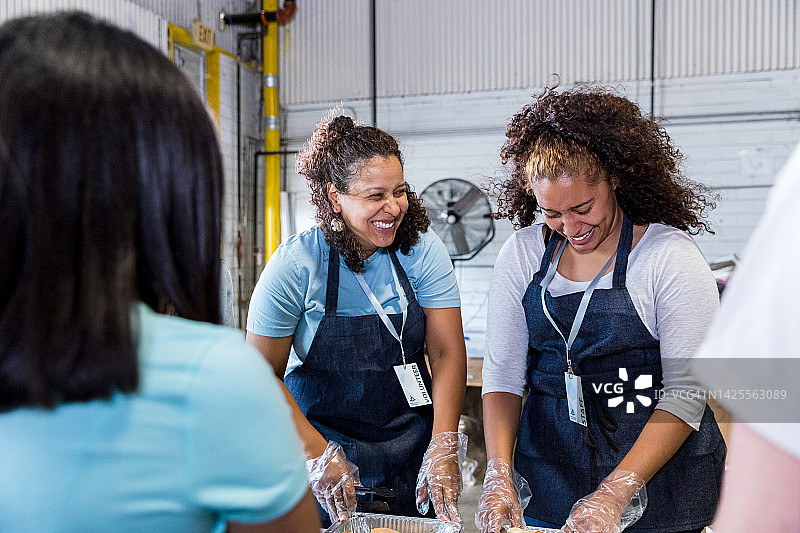 母亲在活动中为女儿盛食物，面带微笑图片素材