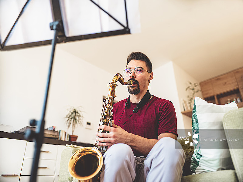 年轻男音乐家在家练习萨克斯管图片素材