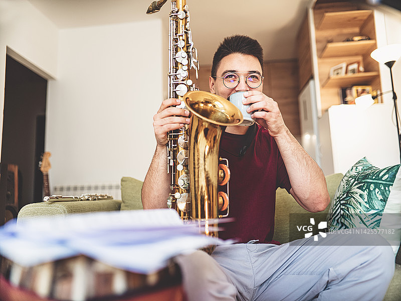 在家练习的年轻男音乐家，咖啡休息时间图片素材