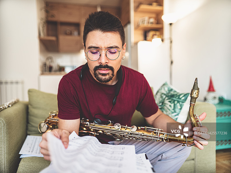 年轻男音乐家在家练习萨克斯管图片素材