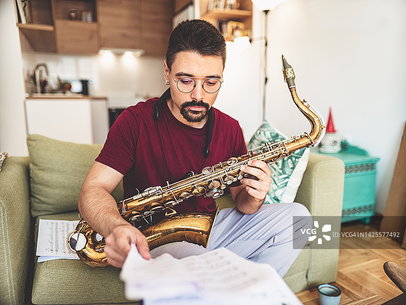 年轻男音乐家在家练习萨克斯管图片素材