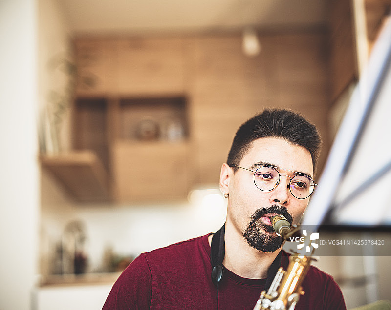 年轻男音乐家在家练习萨克斯管图片素材
