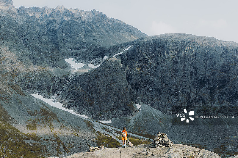 女徒步旅行者和狗欣赏挪威雄伟的山脉图片素材