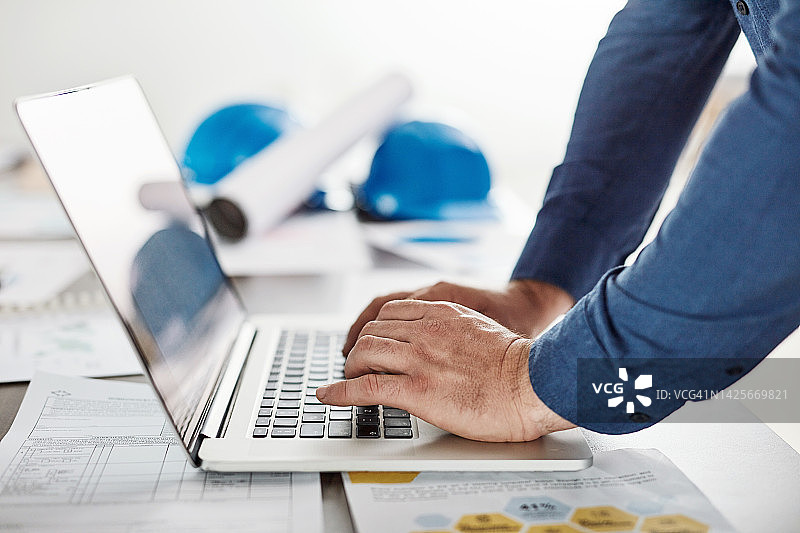 建筑师、工程师或商人在办公室使用笔记本电脑进行建筑设计。建筑规划师使用电脑应用程序或网站绘制规划图的特写镜头图片素材