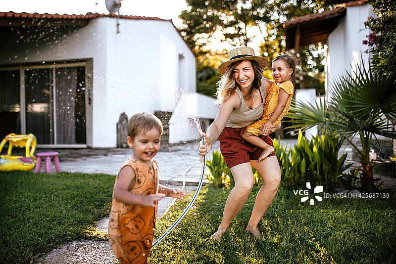在后院用花园软管享受家庭乐趣图片素材