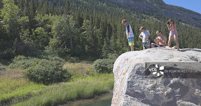 朋友们准备从岩石跳入池塘图片素材